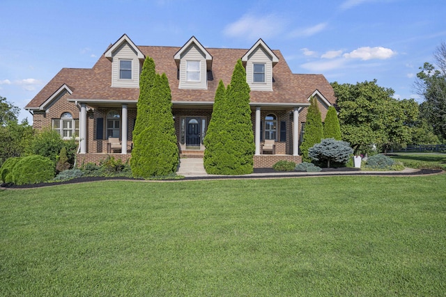 new england style home with a shingled roof, brick siding, and a front lawn