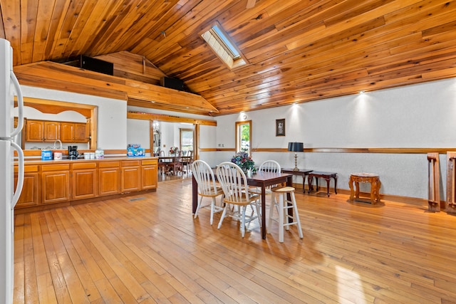 dining room featuring vaulted ceiling with skylight, light hardwood / wood-style floors, and wood ceiling