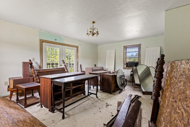 living room featuring cooling unit, french doors, a textured ceiling, and a chandelier