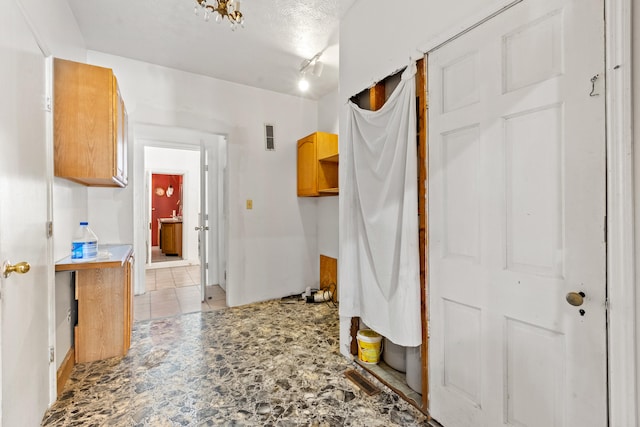 corridor with light tile patterned flooring and a textured ceiling