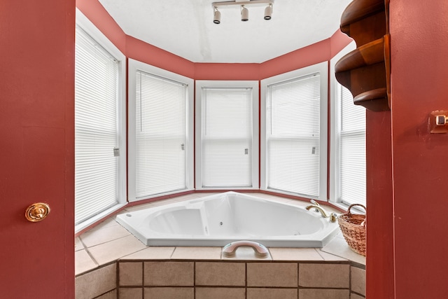 bathroom featuring rail lighting, tiled bath, and plenty of natural light