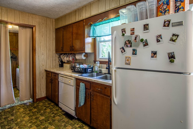 kitchen featuring a textured ceiling, white appliances, sink, and dark tile patterned floors