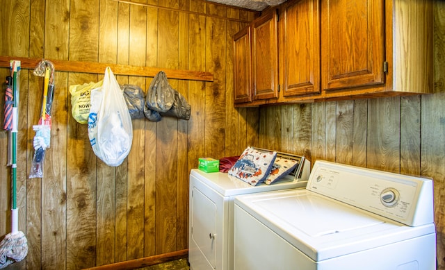 laundry room featuring cabinets, washer and dryer, and wood walls