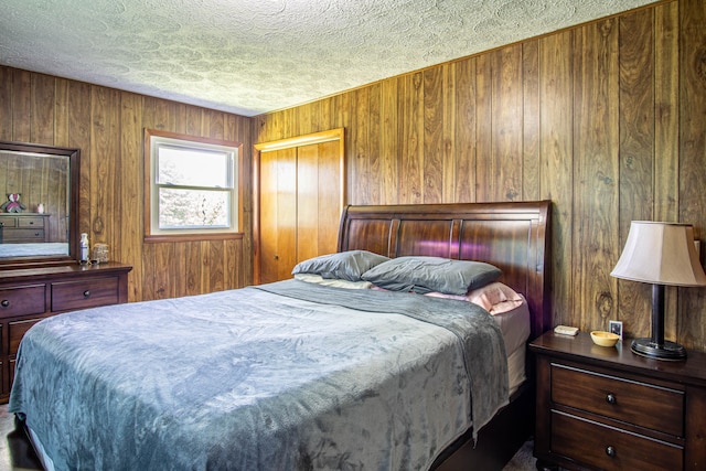 bedroom featuring wood walls, a textured ceiling, and a closet