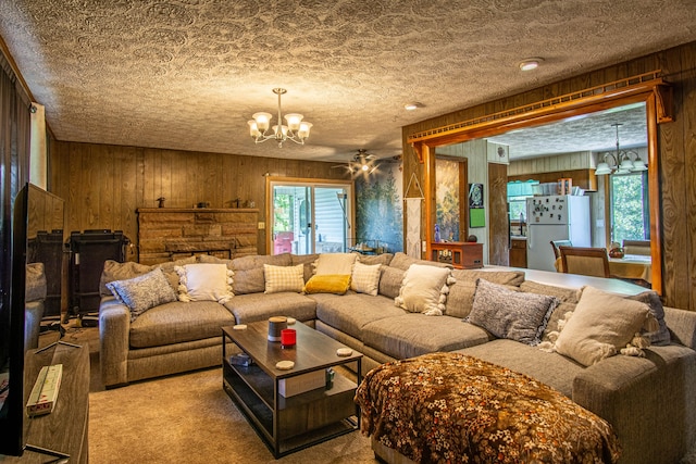 living room with wood walls, a textured ceiling, and ceiling fan with notable chandelier