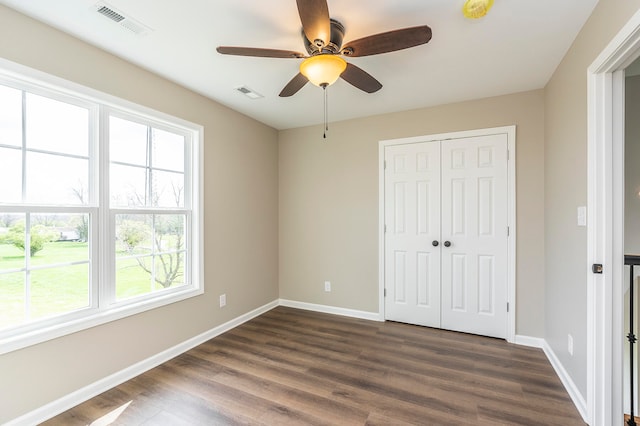 unfurnished bedroom with a closet, dark wood-type flooring, and ceiling fan