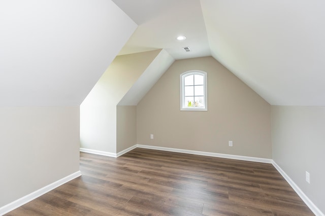 additional living space with hardwood / wood-style flooring and vaulted ceiling