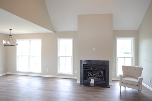 unfurnished living room featuring an inviting chandelier, lofted ceiling, and hardwood / wood-style floors