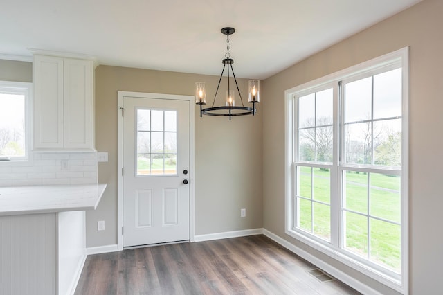 unfurnished dining area with dark hardwood / wood-style floors and a chandelier