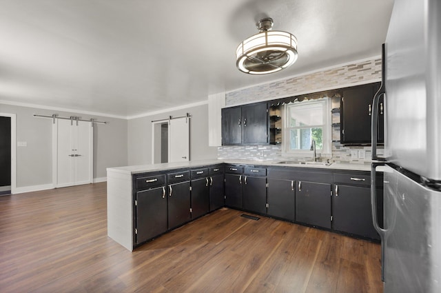 kitchen with dark hardwood / wood-style flooring, tasteful backsplash, stainless steel fridge, and a barn door