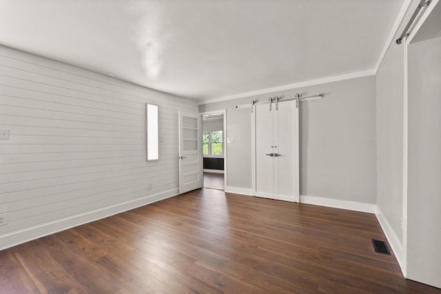 unfurnished bedroom featuring hardwood / wood-style floors and a barn door