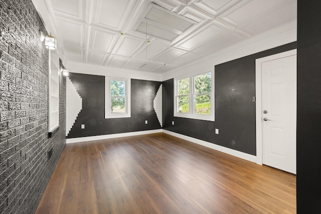 empty room featuring hardwood / wood-style flooring and brick wall