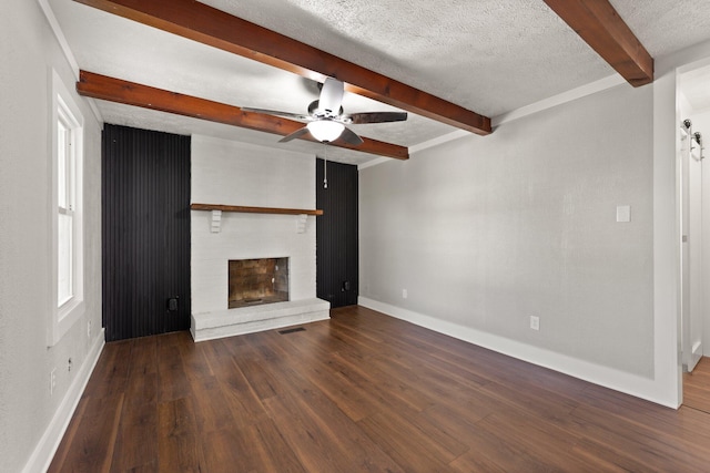 unfurnished living room with a fireplace, beam ceiling, dark hardwood / wood-style flooring, and a textured ceiling