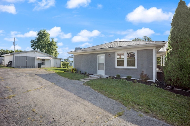 single story home featuring a garage, an outbuilding, and a front yard