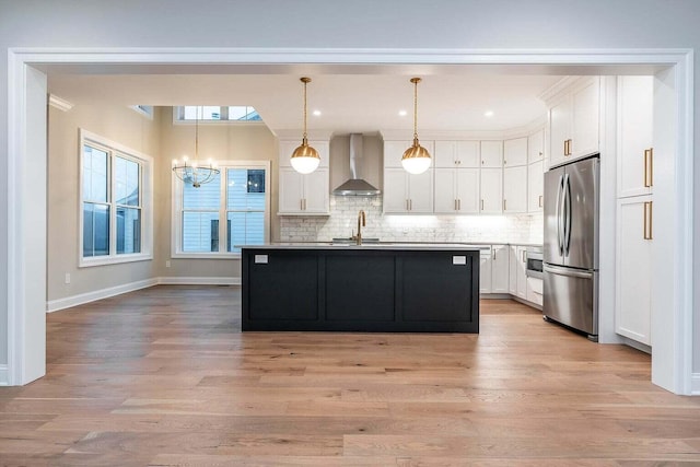 kitchen featuring wall chimney exhaust hood, light hardwood / wood-style flooring, stainless steel fridge, and sink