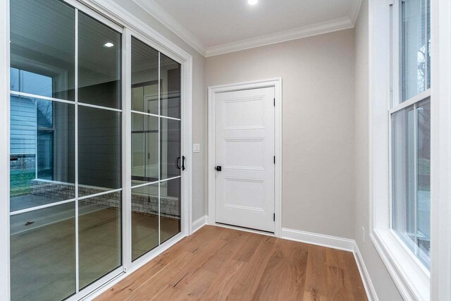 doorway to outside with crown molding and wood-type flooring