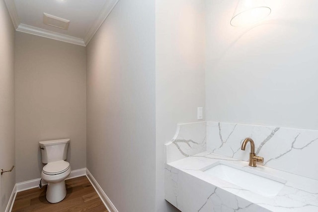 bathroom with crown molding, hardwood / wood-style flooring, and toilet