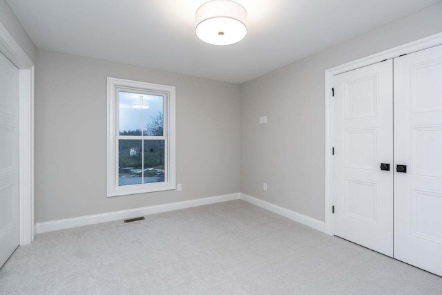 unfurnished bedroom with light colored carpet and a closet