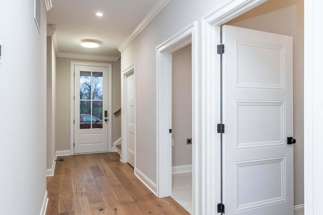 hallway with light wood-type flooring and ornamental molding