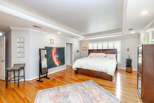 bedroom with crown molding, a raised ceiling, and light hardwood / wood-style flooring