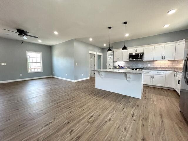 kitchen featuring a center island, hardwood / wood-style flooring, tasteful backsplash, ceiling fan, and white cabinetry