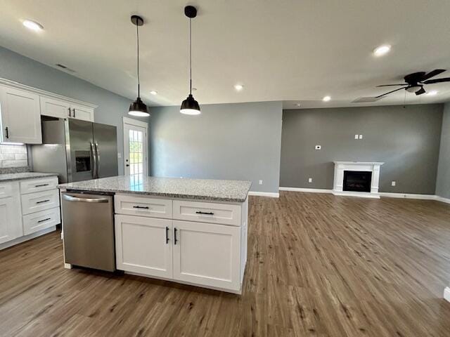 kitchen featuring a center island, appliances with stainless steel finishes, hardwood / wood-style flooring, ceiling fan, and white cabinets