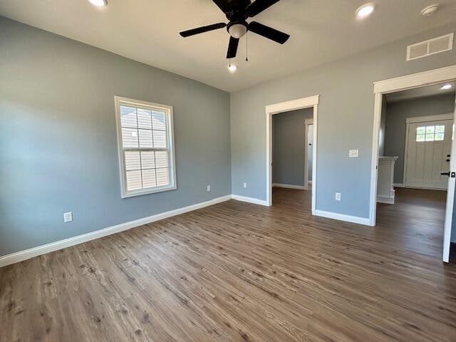 unfurnished bedroom with ceiling fan, hardwood / wood-style flooring, and multiple windows