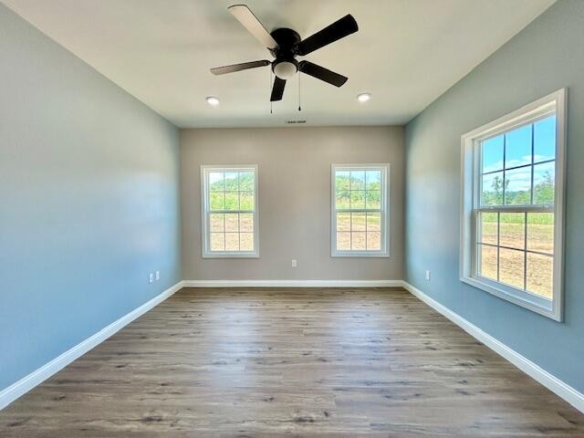 unfurnished room featuring ceiling fan, a healthy amount of sunlight, and hardwood / wood-style floors