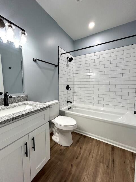 full bathroom with tiled shower / bath combo, wood-type flooring, toilet, and vanity