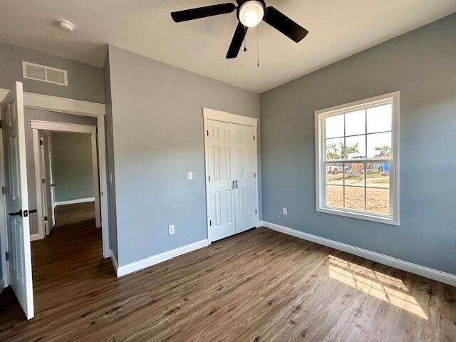 unfurnished bedroom featuring ceiling fan, a closet, and dark hardwood / wood-style floors