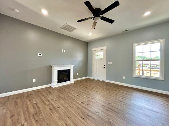 unfurnished living room with baseboards, visible vents, and a glass covered fireplace