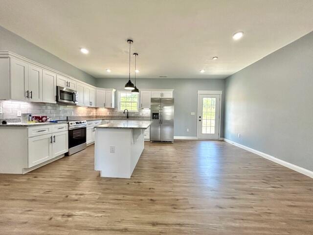 kitchen with appliances with stainless steel finishes, plenty of natural light, and white cabinetry