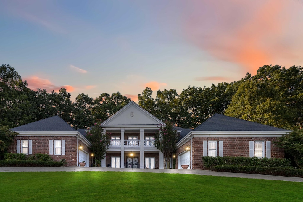 greek revival inspired property with a balcony and a yard