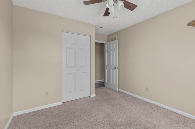 unfurnished bedroom featuring a textured ceiling, carpet, a closet, and ceiling fan