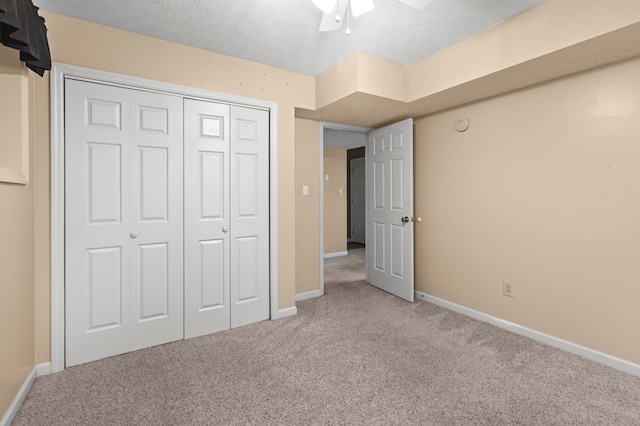 unfurnished bedroom featuring ceiling fan, a textured ceiling, a closet, and light colored carpet