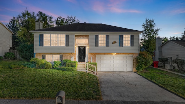 bi-level home featuring a garage and a yard