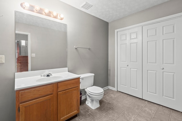 bathroom featuring a textured ceiling, toilet, tile patterned floors, and vanity