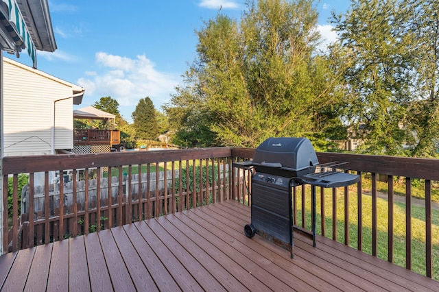 wooden terrace with a yard and a grill