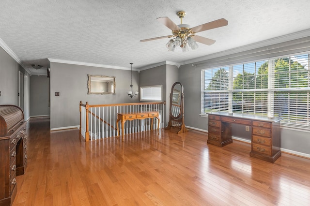 empty room with ceiling fan, a textured ceiling, crown molding, and hardwood / wood-style flooring