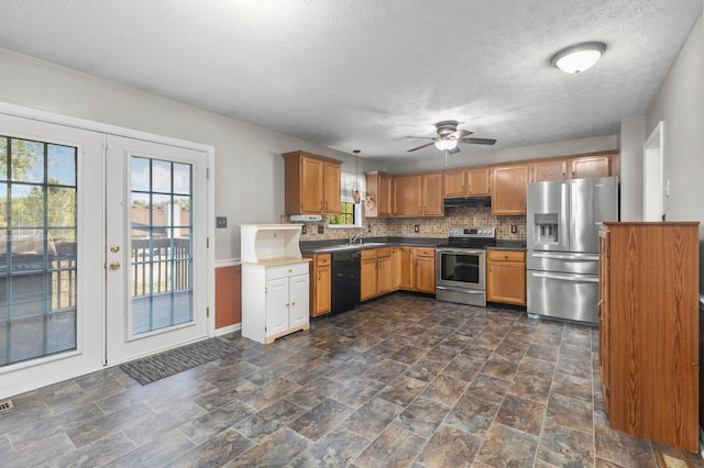 kitchen with dark tile patterned flooring, pendant lighting, stainless steel appliances, ceiling fan, and sink