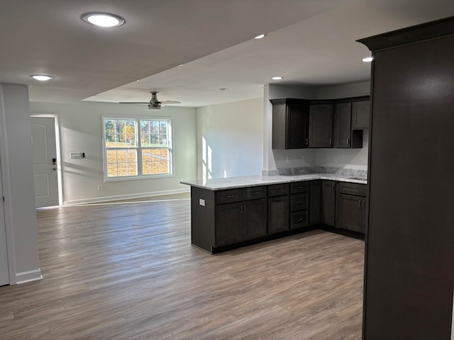 kitchen with light hardwood / wood-style floors, kitchen peninsula, dark brown cabinets, and ceiling fan