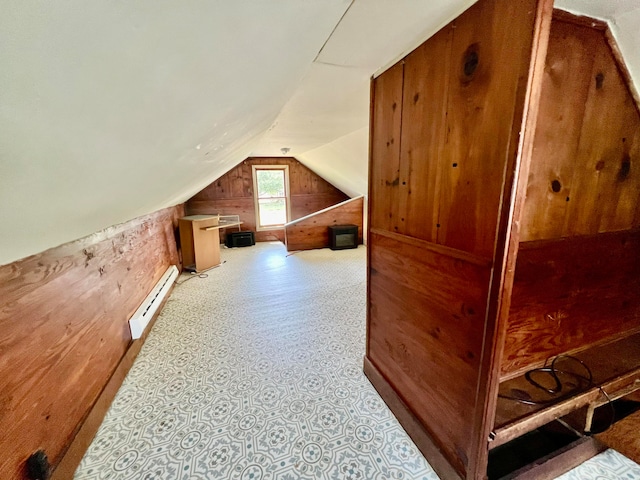 additional living space with wood walls, lofted ceiling, and baseboard heating