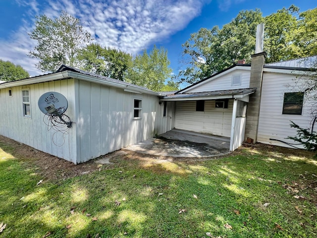 back of house with a patio and a lawn