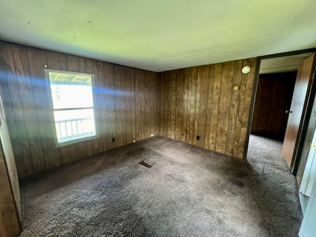 unfurnished room featuring wooden walls and carpet