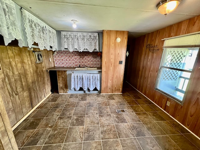 interior space featuring dark tile patterned flooring, wood walls, and sink