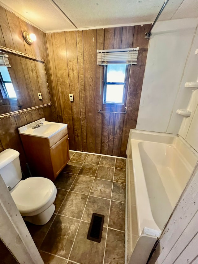 bathroom with wood walls, toilet, tile patterned floors, and vanity