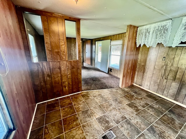 interior space with wooden walls and dark tile patterned floors