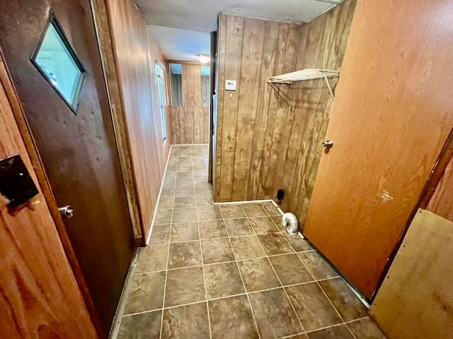 hall featuring tile patterned floors and wooden walls