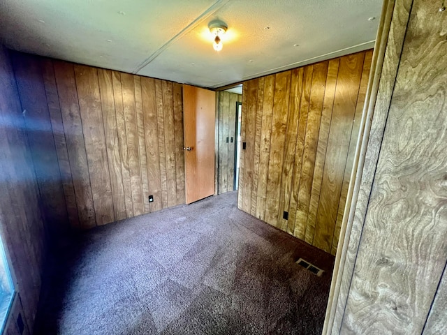 unfurnished room with wood walls and carpet