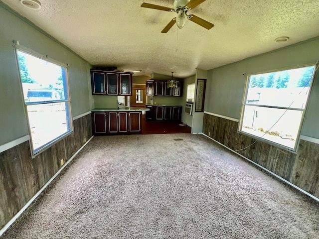 unfurnished living room with ceiling fan, plenty of natural light, and carpet